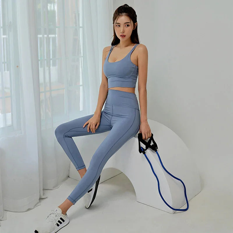 Woman in light blue seamless sports bra and leggings set poses indoors with resistance band
